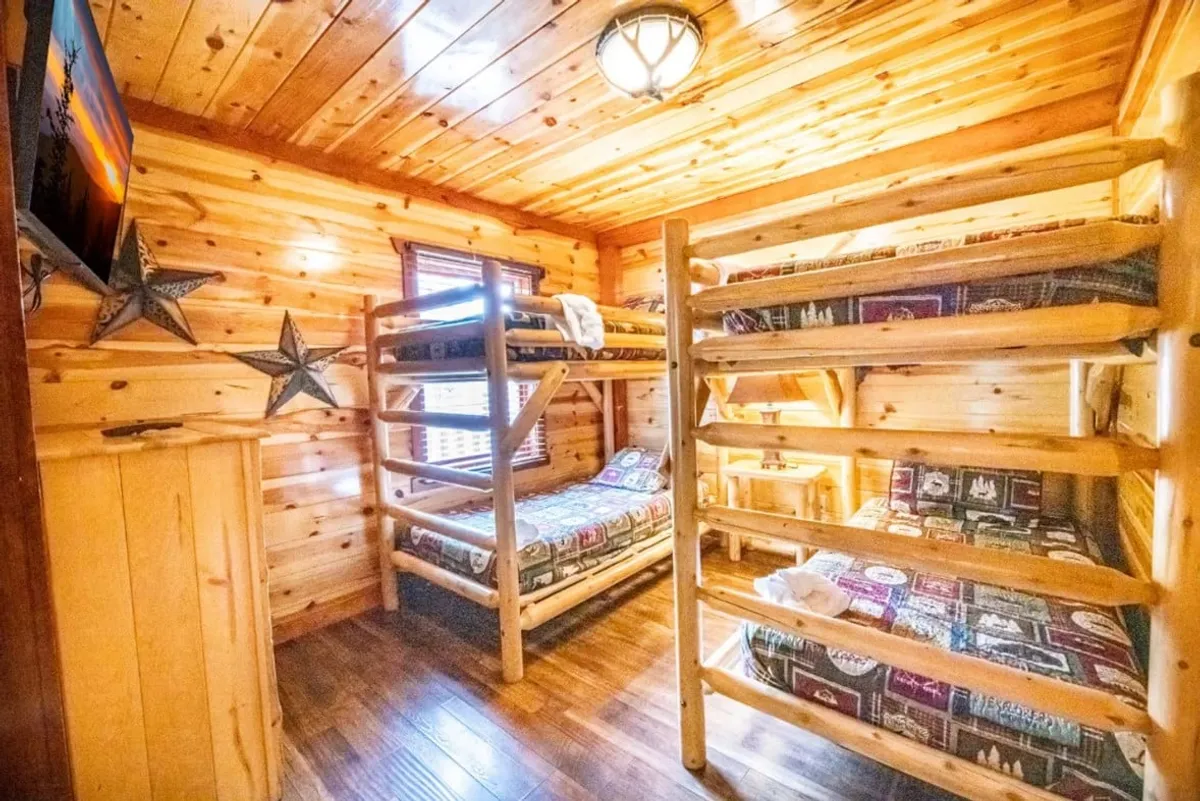 This interior scene features a bunk bed with wooden paneling, playful decorative stars, and a TV. The space is inviting and fun, ideal for younger guests or families seeking a playful, cozy sleeping arrangement.