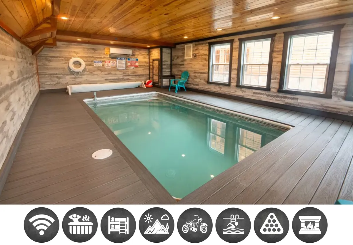 The image showcases a stunning indoor swimming pool at the heart of a wooden cabin, with soaring timber ceilings and expansive windows that bathe the space in natural light. A plush blue chair sits poolside, inviting guests to relax and soak in the peaceful mountain atmosphere. The scene exudes a sense of calm and enjoyment, perfectly suited for family fun, sunset swims, and unwinding after a day of adventure in the Smokies.
