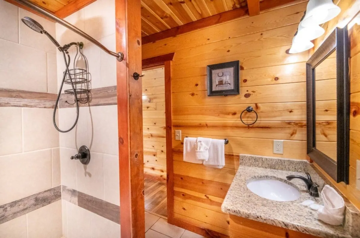 A serene bathroom interior with a spacious shower area, vanity with sink, and soothing wooden walls. The clean design and soft lighting evoke feelings of relaxation and privacy.