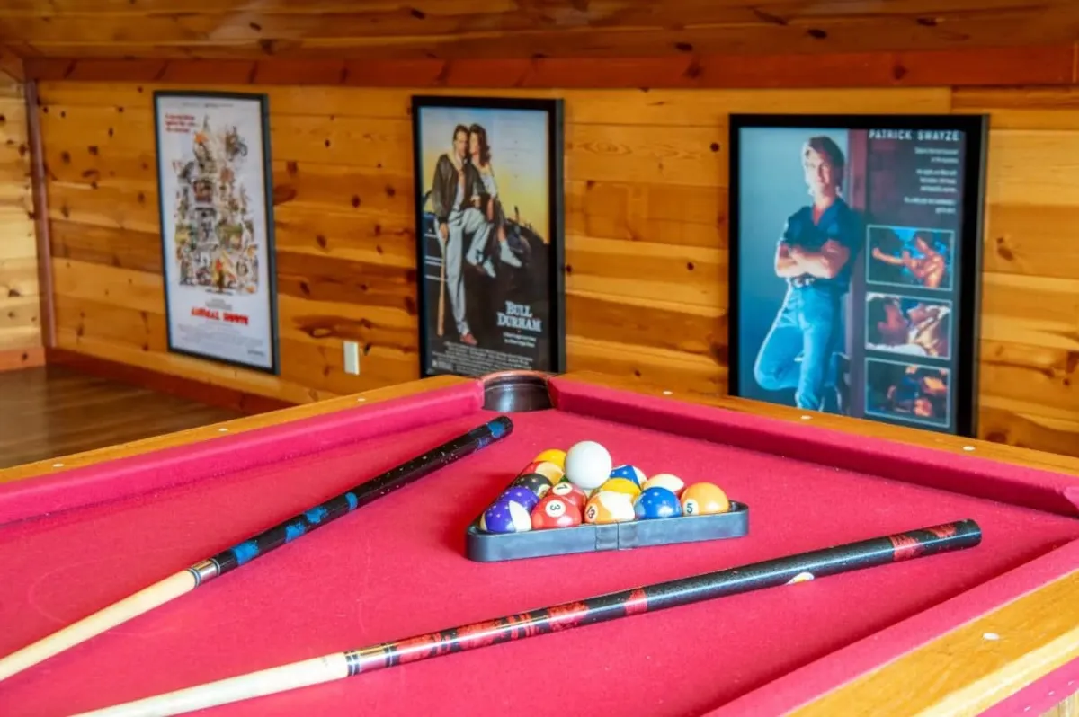 An interior game room featuring a pool table, movie posters, and billiard cues, creating a relaxed and entertaining environment perfect for family gatherings and movie marathons.
